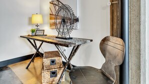 Une pièce comprenant un bureau, une chaise, une lampe et une grande œuvre d’art accrochée au mur.