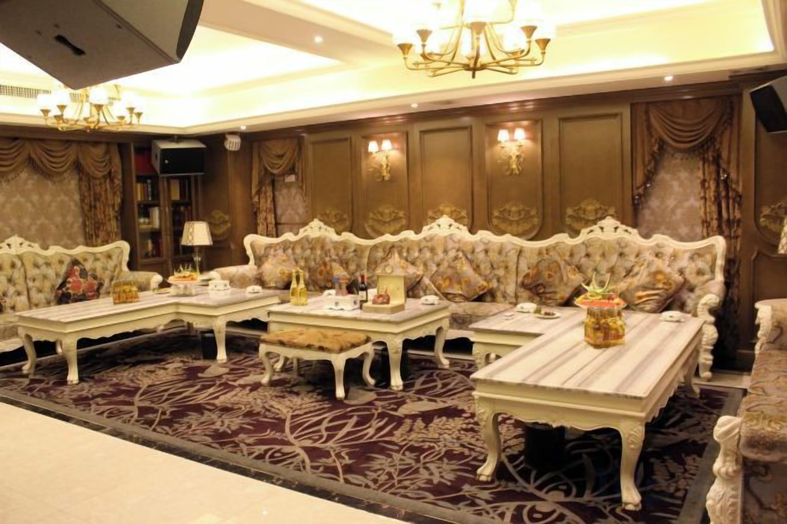 A luxurious room with ornate sofas, a central coffee table, and a chandelier.
