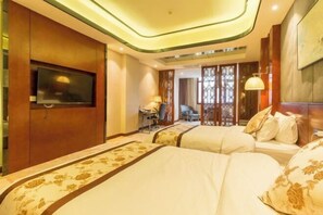 A hotel room with two beds, a TV mounted on the wall, a desk with a chair, and a decorative partition. - Mingshi Hotel (Xingan)