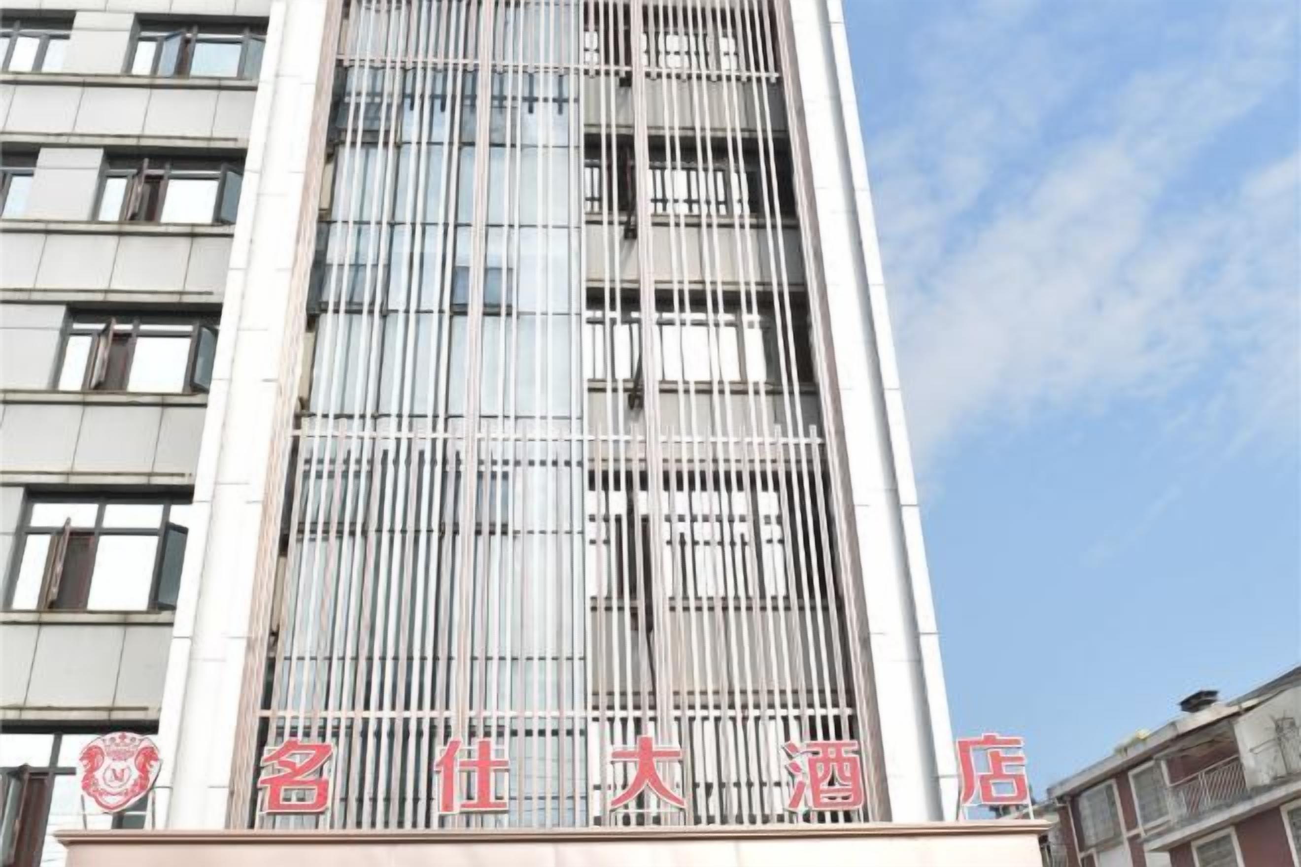 A tall building with a modern facade, featuring a series of vertical lines and a clear sky in the background.