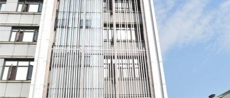 A tall building with a modern facade, featuring a series of vertical lines and a clear sky in the background.