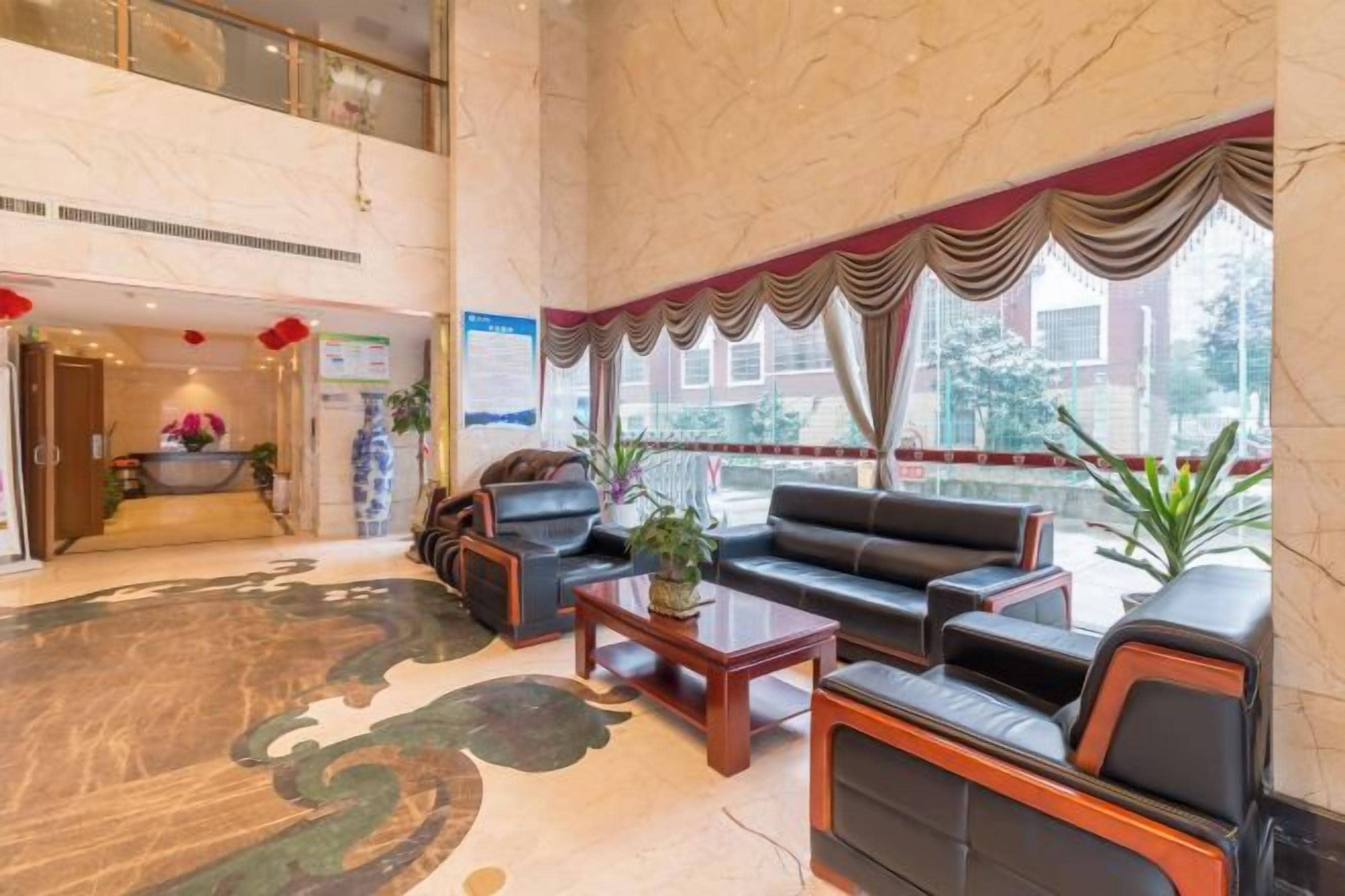 A lobby with a reception desk, seating area, and large windows.