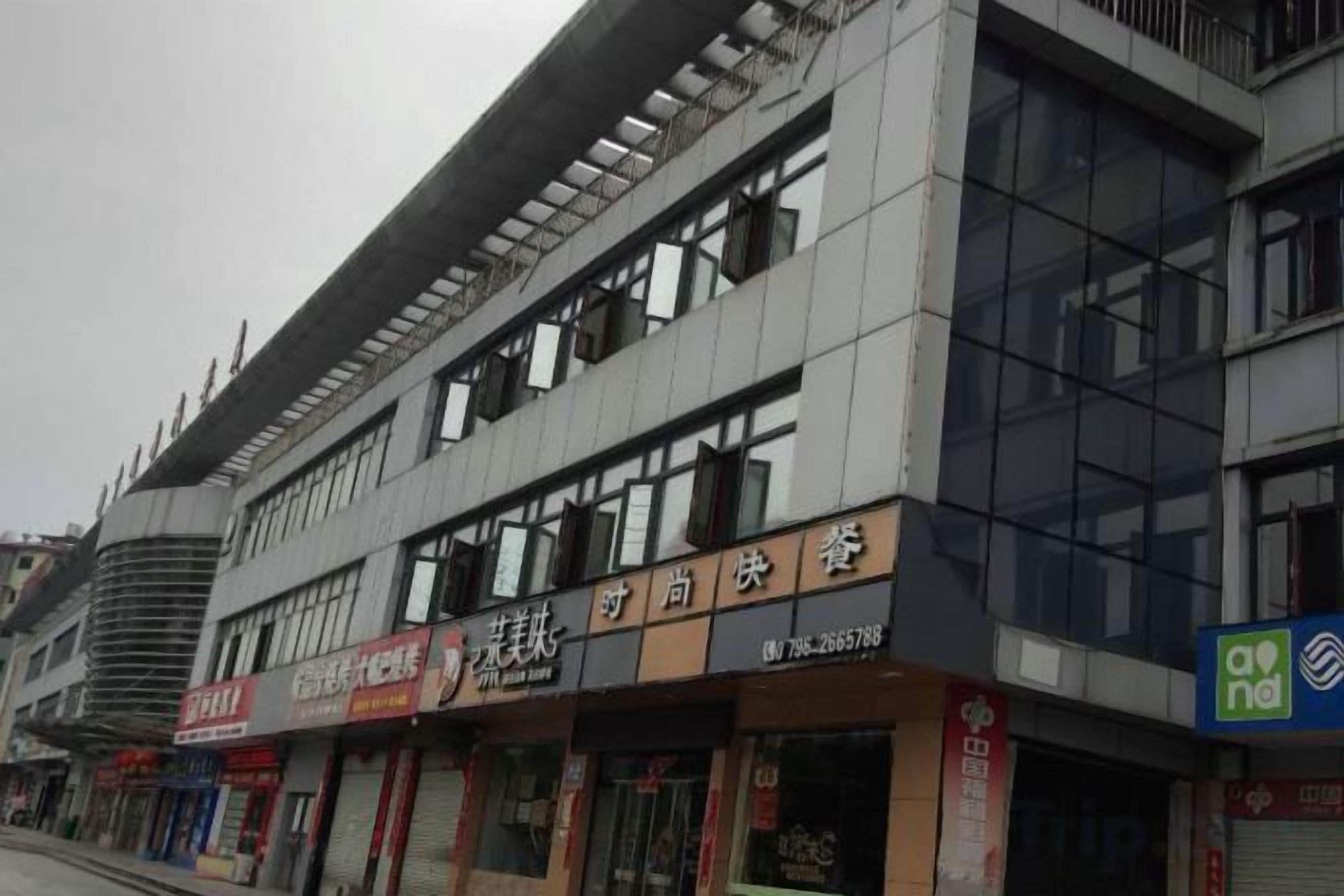 A multi-story building with commercial establishments on the ground floor, including a restaurant and a shop.