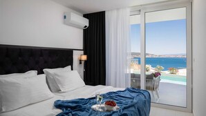 Et hotelværelse med seng, et sengebord med lampe, en balkon med havudsigt og en aircondition på væggen.