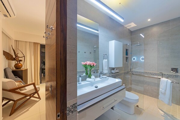 Un baño moderno con cabina de ducha de vidrio, un lavamanos blanco y un inodoro.