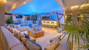 A spacious living area with a large sofa, a coffee table, and a bar area with stools. - Loft 268 "Beautiful Modern Condominium" in  Romantic Zone, Puerto Vallarta. (Puerto Vallarta)