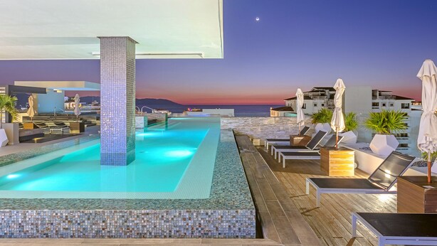 A rooftop infinity pool with a view of the sea at sunset, lounge chairs, and umbrellas. - Loft 268 "Beautiful Modern Condominium" in  Romantic Zone, Puerto Vallarta. (Puerto Vallarta)