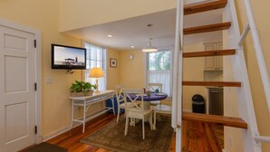 A cozy living room with a dining area, a staircase, and a kitchen. - Loft Villa Steps from Duval! (Key West)