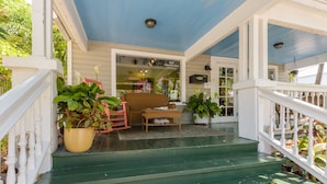 A porch with green steps, a wicker chair, and a potted plant. - Loft Villa Steps from Duval! (Key West)