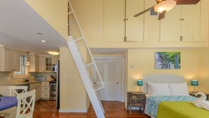 A bedroom with a bed, a nightstand, a lamp, a swan decoration, and a painting of bicycles on the wall. - Loft Villa Steps from Duval! (Key West)