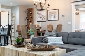 Un salon moderne avec un canapé gris, une table basse en bois et un lustre.