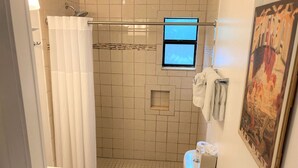 Une salle de bain avec une douche, des toilettes et une petite fenêtre.