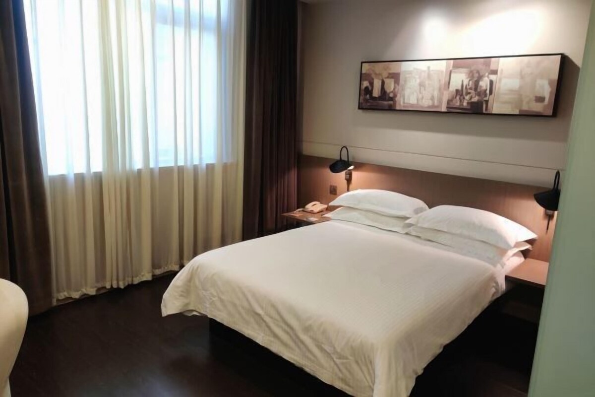 Ein Hotelzimmer mit Bett, Nachttisch, Lampe und einem Wandbild.