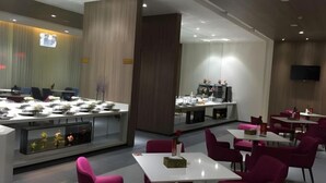 A modern restaurant with white tables and red chairs, a counter with food displays, and a TV mounted on the wall. - Jinjiang Inn Select (Taixing Runtai South Road) (Taixing)