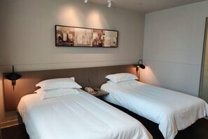 Ein Hotelzimmer mit zwei Einzelbetten, einem Nachttisch mit Telefon und einem Wandbild.