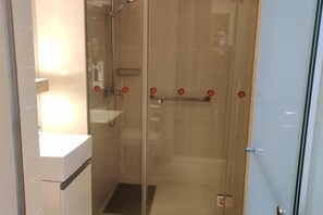 Eine Duschkabine aus Glas mit Handtuchhalter und einer kleinen Ablage.