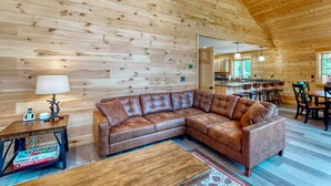 A wooden interior with a sectional sofa, a small table, and a lamp. - Gorgeous dog-friendly cabin with great view, deck, hot tub, & gas fireplace (Kingfield)