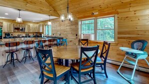 A spacious kitchen with wooden cabinets, a central island, and bar stools. - Gorgeous dog-friendly cabin with great view, deck, hot tub, & gas fireplace (Kingfield)