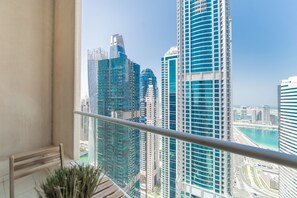 A balcony with a view of modern high-rise buildings and a body of water.