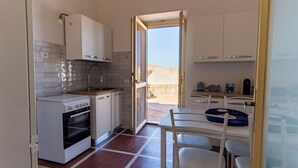 Une cuisine compacte avec des meubles blancs, une cuisinière et un évier. On y trouve également un coin repas avec une table et des chaises.