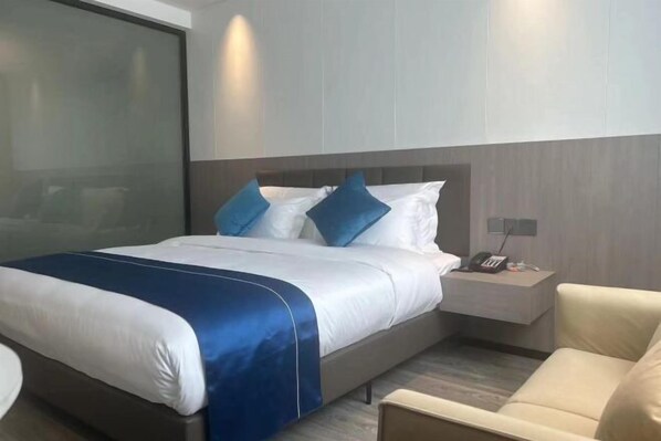 A modern hotel room with a large bed, a bedside table with a phone, and a chair. - Laiyueke Hotel (Shenzhen)