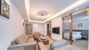 A modern hotel room with a sofa set, a coffee table, a TV, and a bed with a headboard. - Laiyueke Hotel (Shenzhen)