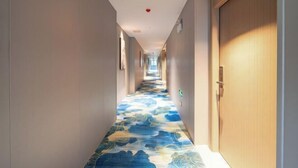 A hotel hallway with a patterned carpet, doors on both sides, and a fire alarm on the ceiling. - Laiyueke Hotel (Shenzhen)