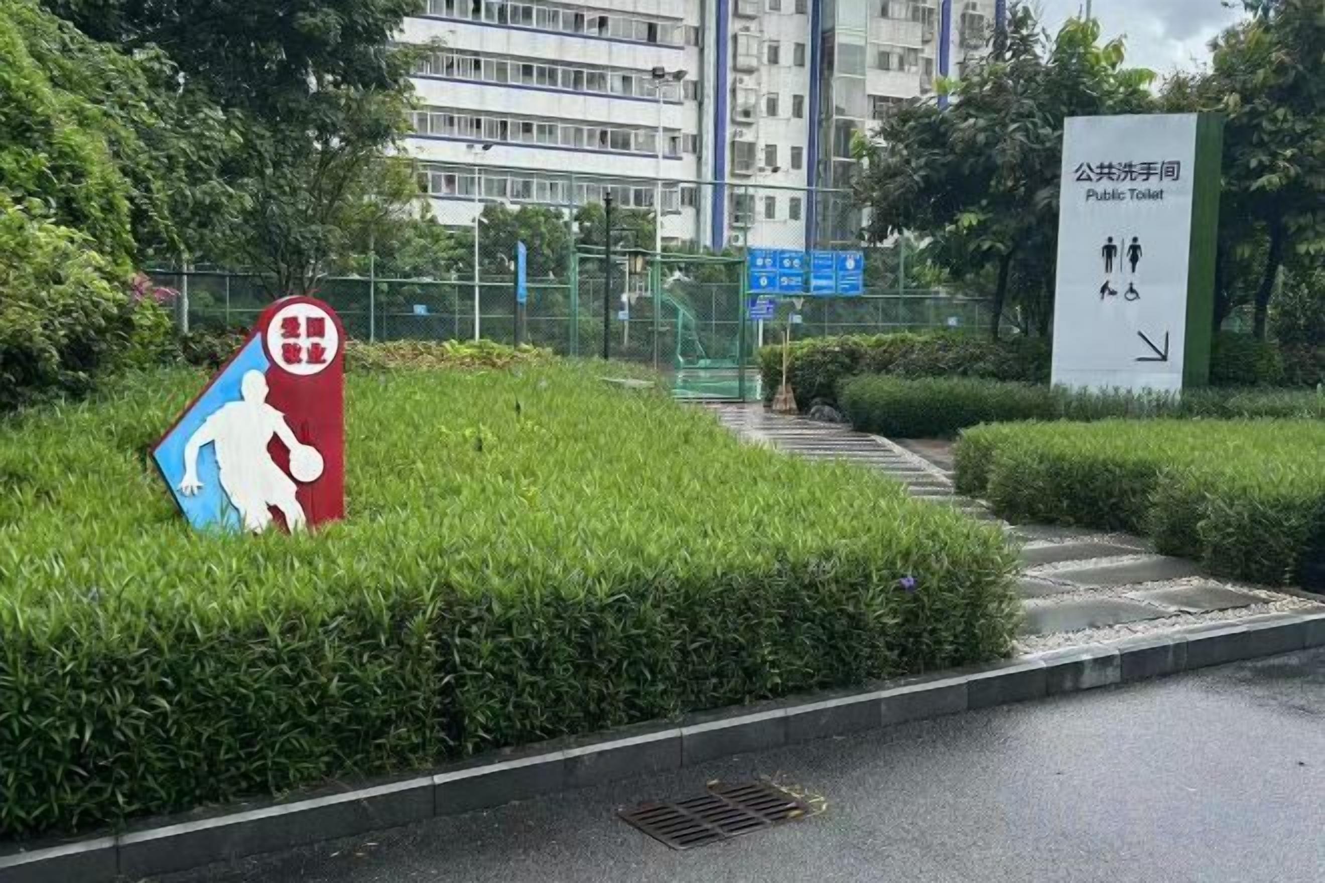 A public toilet sign with directional arrows and a basketball court sign.