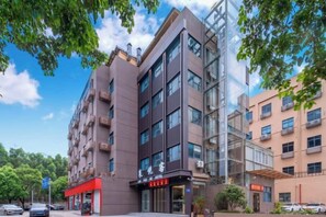 Un edificio de varios pisos con fachada de vidrio, un toldo rojo y un letrero con caracteres chinos.