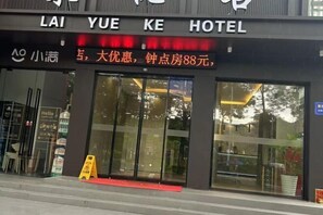 The exterior of Lai Yue Ke Hotel with a large glass entrance and a red carpet leading inside.