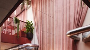 Eine moderne Hotelhalle mit roten Sitzgelegenheiten, einem großen Spiegel und einem Blumentopf.