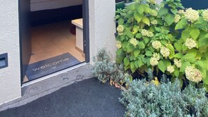 Ein modernes Haus mit sichtbarem Schlafzimmer, Klingel und einem Garten mit Hortensien.