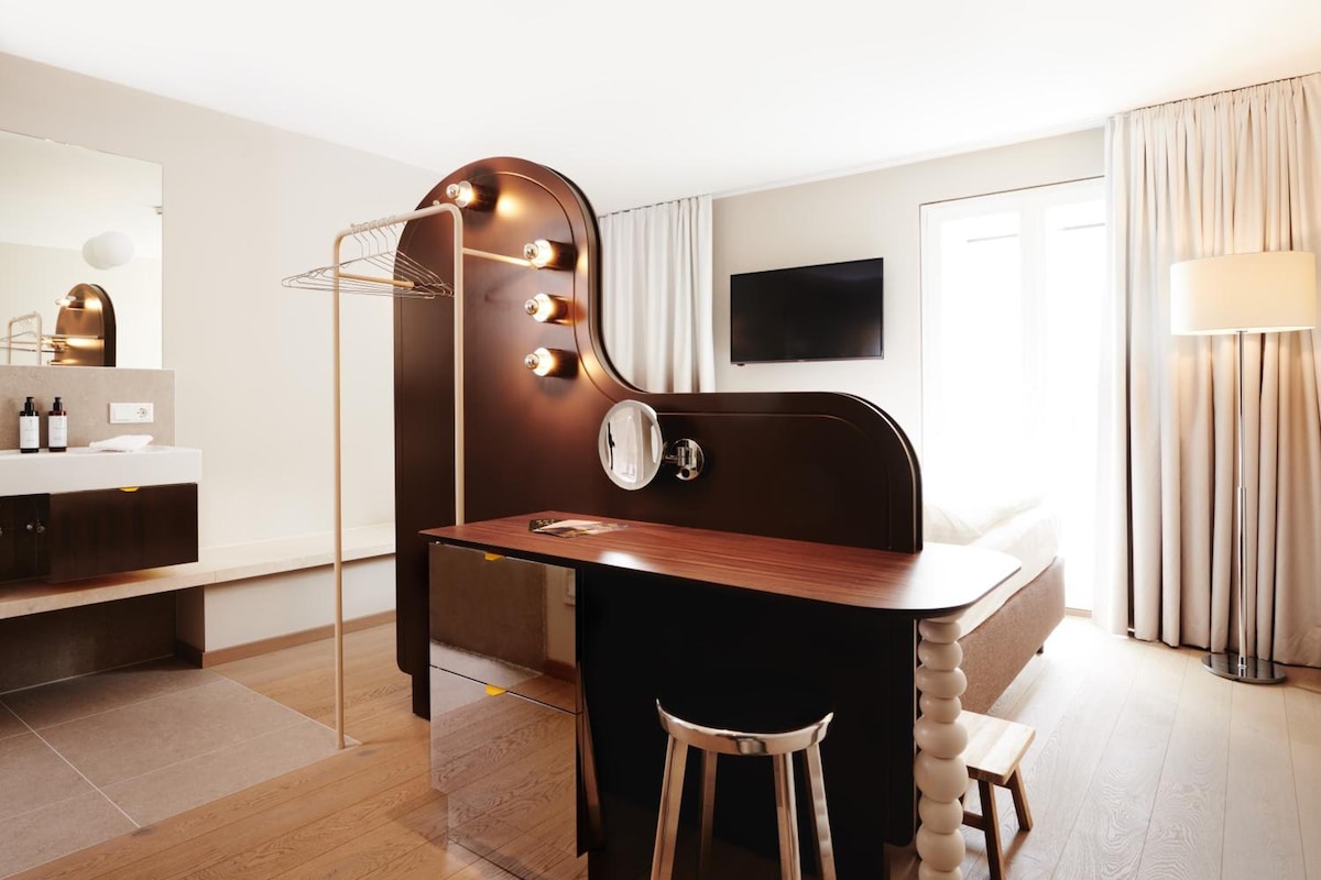 A modern hotel room with a vanity, mirror, and lighting.