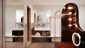 Ein modernes Badezimmer mit Waschtisch, einem beleuchteten Spiegel und einem Handtuchhalter.