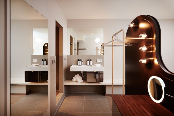 A modern bathroom with a vanity, a mirror with lights, and a towel rack.
