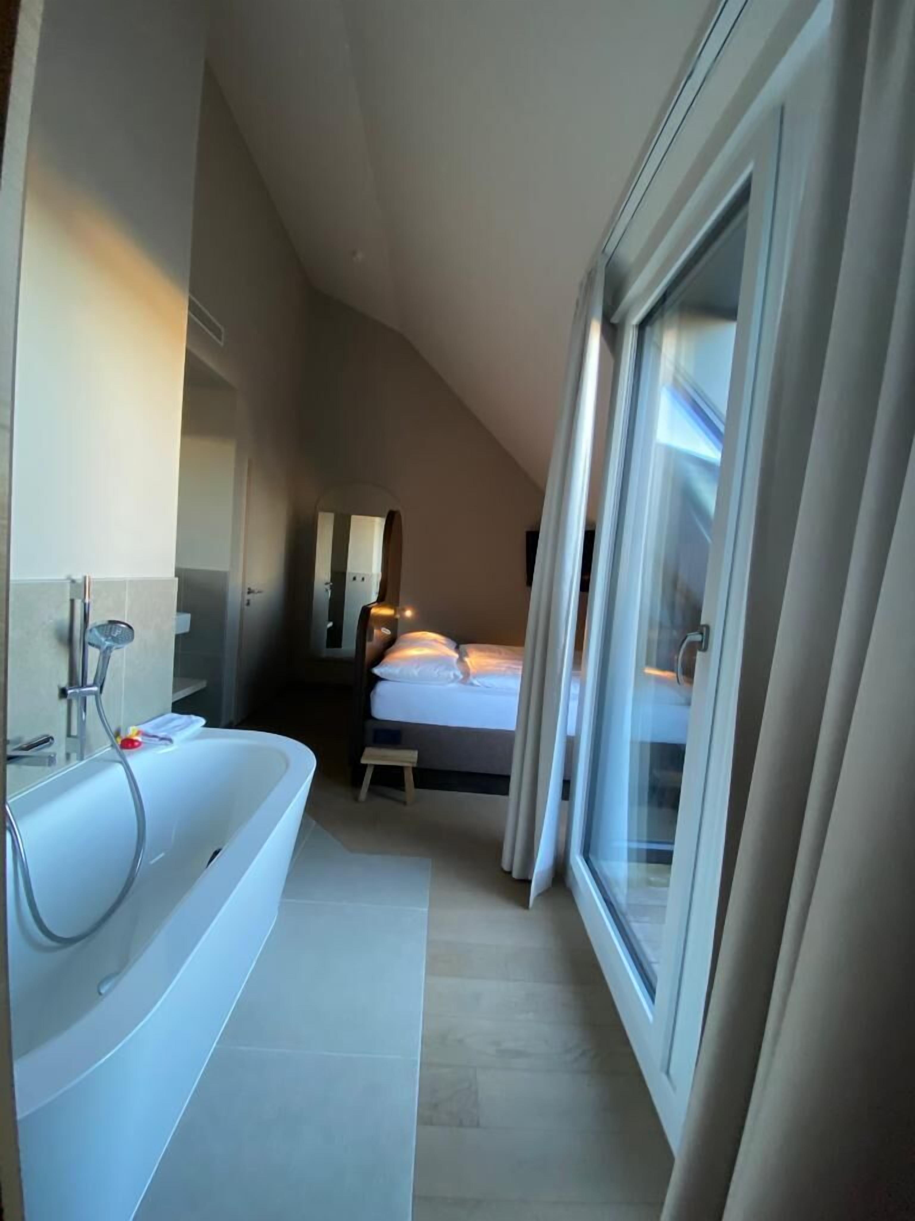A modern bathroom with a freestanding bathtub, a mirror, and a showerhead.