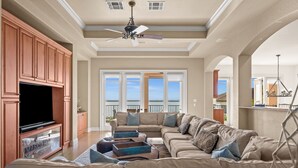 A spacious living room with a large sectional sofa, a flat-screen TV, and a ceiling fan. - Huge Estate, Heated Pool, Water View, King beds, Sleeps 20 (Marco Island)