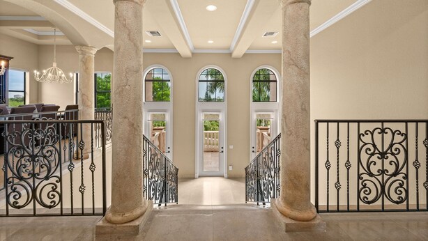 A grand entrance with columns, a chandelier, and a view to the outside. - Huge Estate, Heated Pool, Water View, King beds, Sleeps 20 (Marco Island)