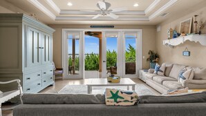 A living room with a sofa, coffee table, and a ceiling fan. - Huge Estate, Heated Pool, Water View, King beds, Sleeps 20 (Marco Island)