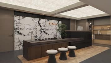A reception area with a marble wall, a reception desk, and three stools.