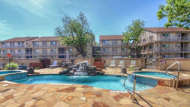 A hotel pool with a waterfall feature, lounge chairs, and a stone-tiled deck. - Poolside Perch | Sleeps 6 | Pet-Friendly (New Braunfels)