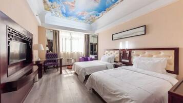 A hotel room with two beds, a TV, a ceiling mural, and a large window.