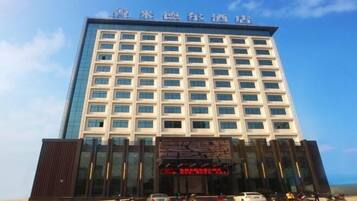 A multi-story hotel with a modern facade, featuring a large digital display at the entrance.