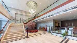 Un vestíbulo espacioso con una escalera de madera, un gran candelabro decorativo y una zona de estar con vistas al agua.