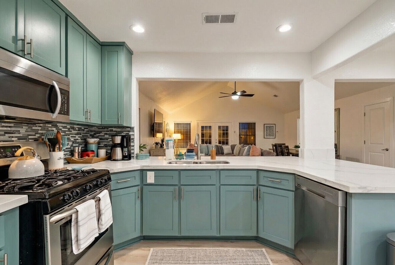 Una cocina con gabinetes verde azulado, una estufa, un microondas y un lavavajillas.