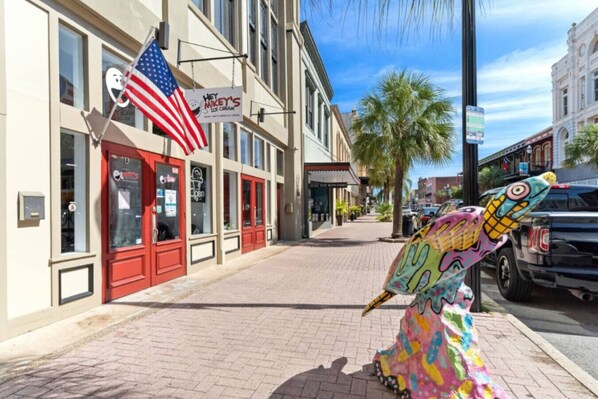 Rua com uma escultura colorida de sorvete, um edifício com porta vermelha e uma bandeira americana.