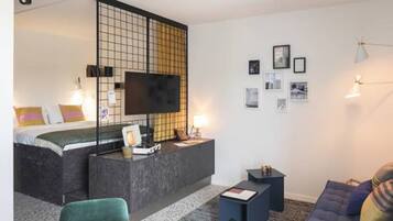 A modern hotel room with a bed, a desk, a TV, and a sofa.