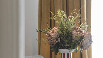 Uma mesa com um vaso de flores, uma luminária pendente e um castiçal listrado.