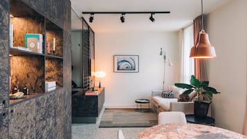 Een moderne woonkamer met een marmeren boekenkast, een ronde tafel, een bank en een potplant.