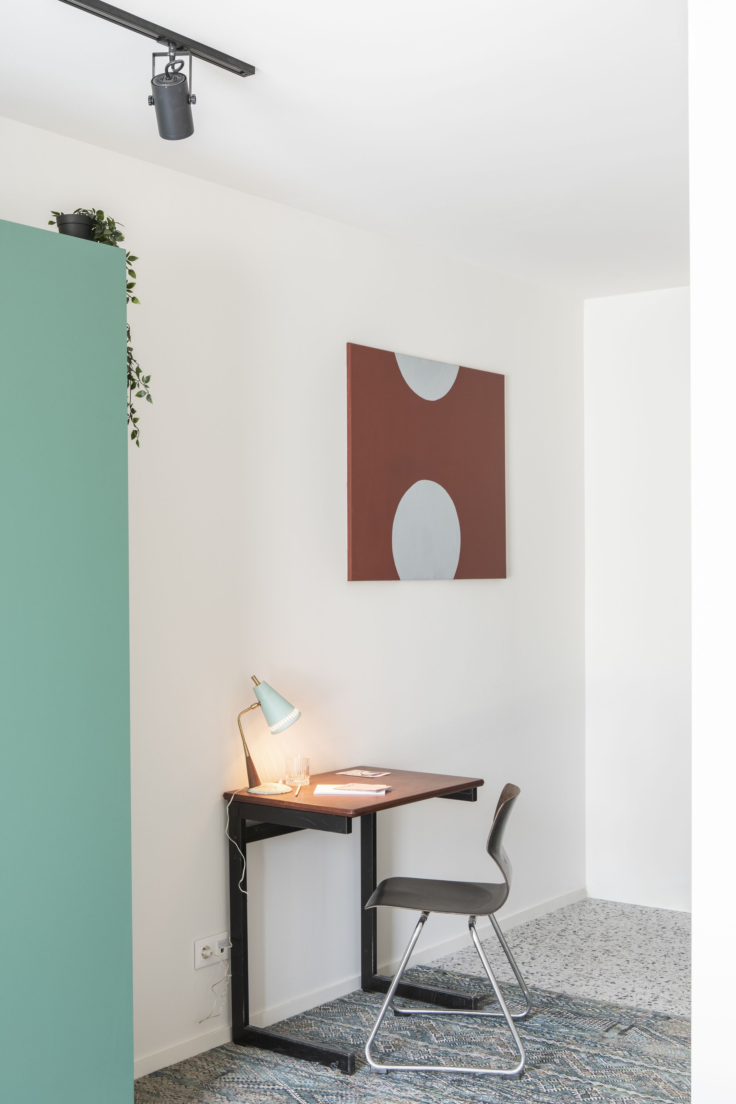 A modern room with a desk, chair, and a wall-mounted abstract painting.